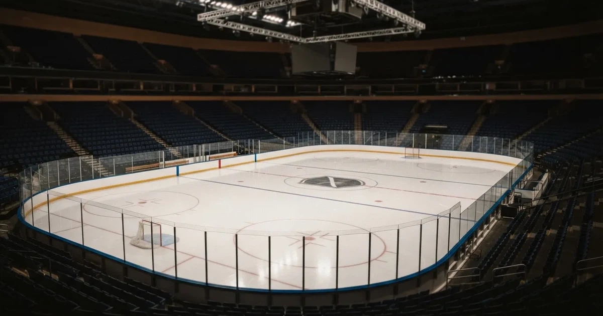 Eine Eishockeyhalle von der Tribüne aus gesehen, spiegelglatte Eisfläche, Banden ohne Schriftzüge, helles Flutlicht.